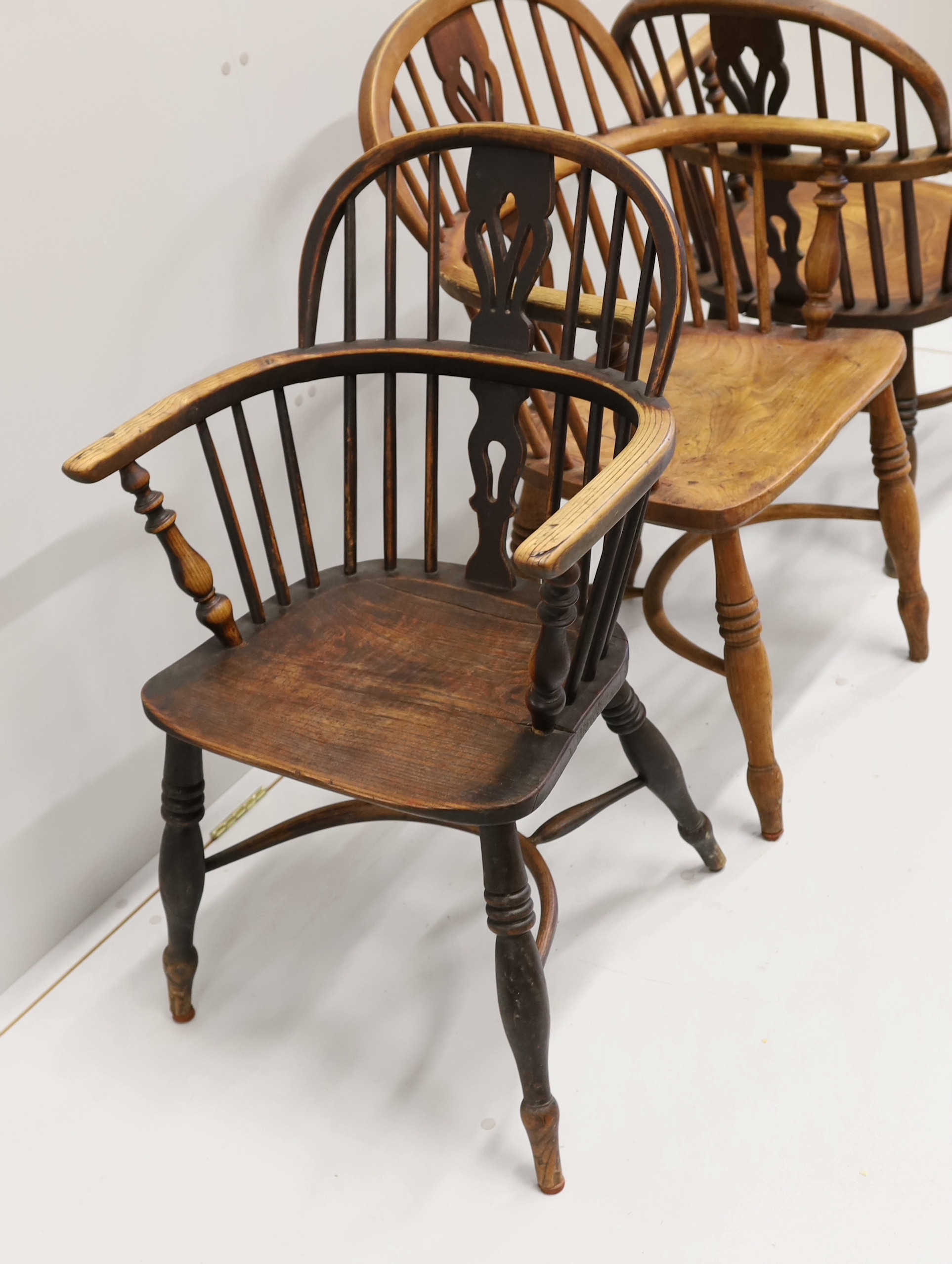Three 19th century Nottingham area Windsor ash and elm elbow chairs with crinoline stretchers, largest width 55cm, depth 39cm, height 95cm